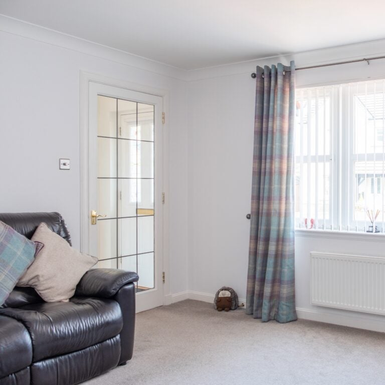 Two Walled View of Modern Lounge in Scottish Housing Developement with Decorated Walls french door and white windows